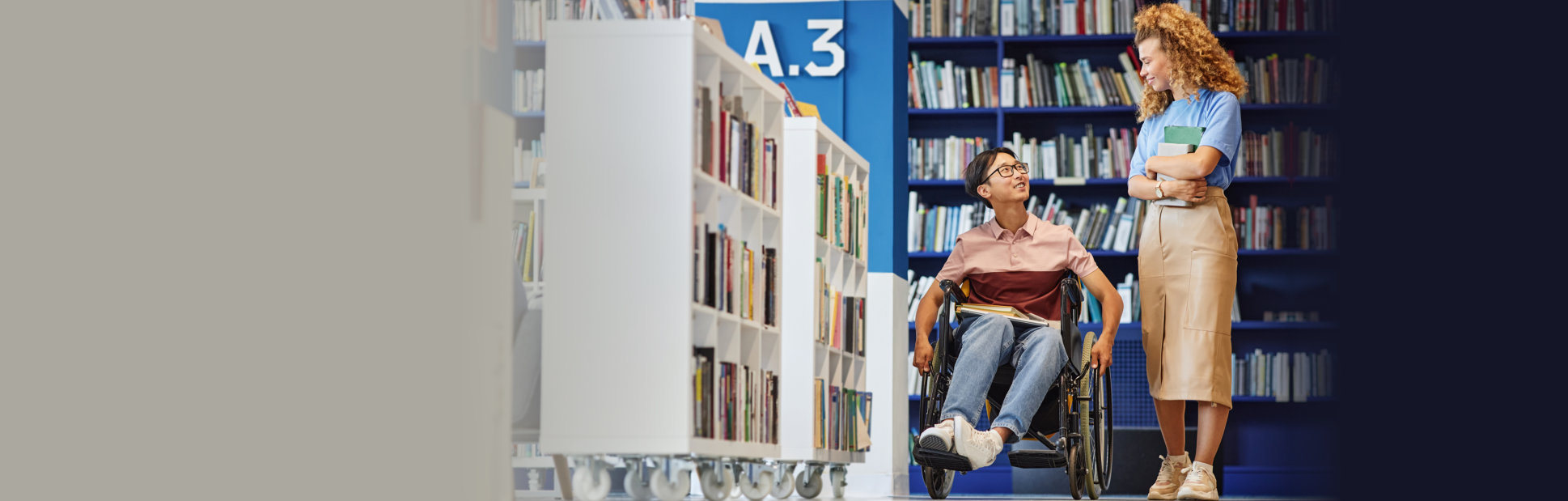 young man with disability using accessible college library and talking to friend